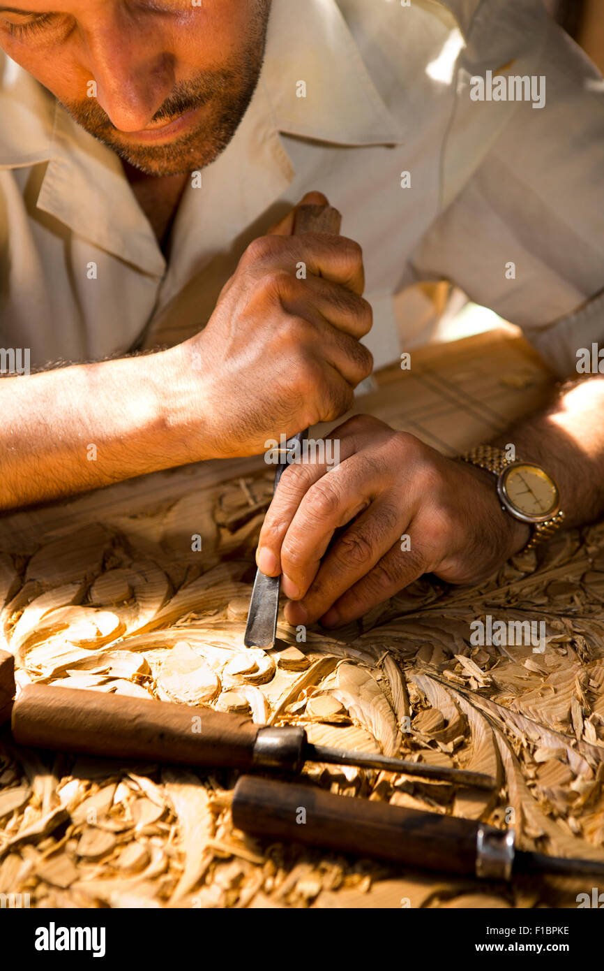 India, Jammu & Kashmir, Srinagar, Old City, crafts, hands of woodcarver carving traditional organic pattern into walnut panel Stock Photo