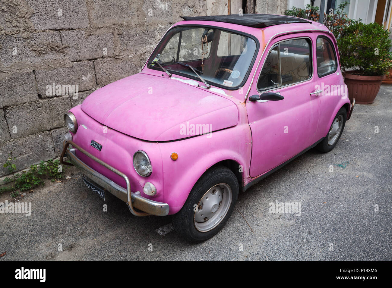 Lacco Ameno, Italy - August 15, 2015: Old pink Fiat Nuova 500 city car produced by the Italian manufacturer Fiat between 1957 an Stock Photo