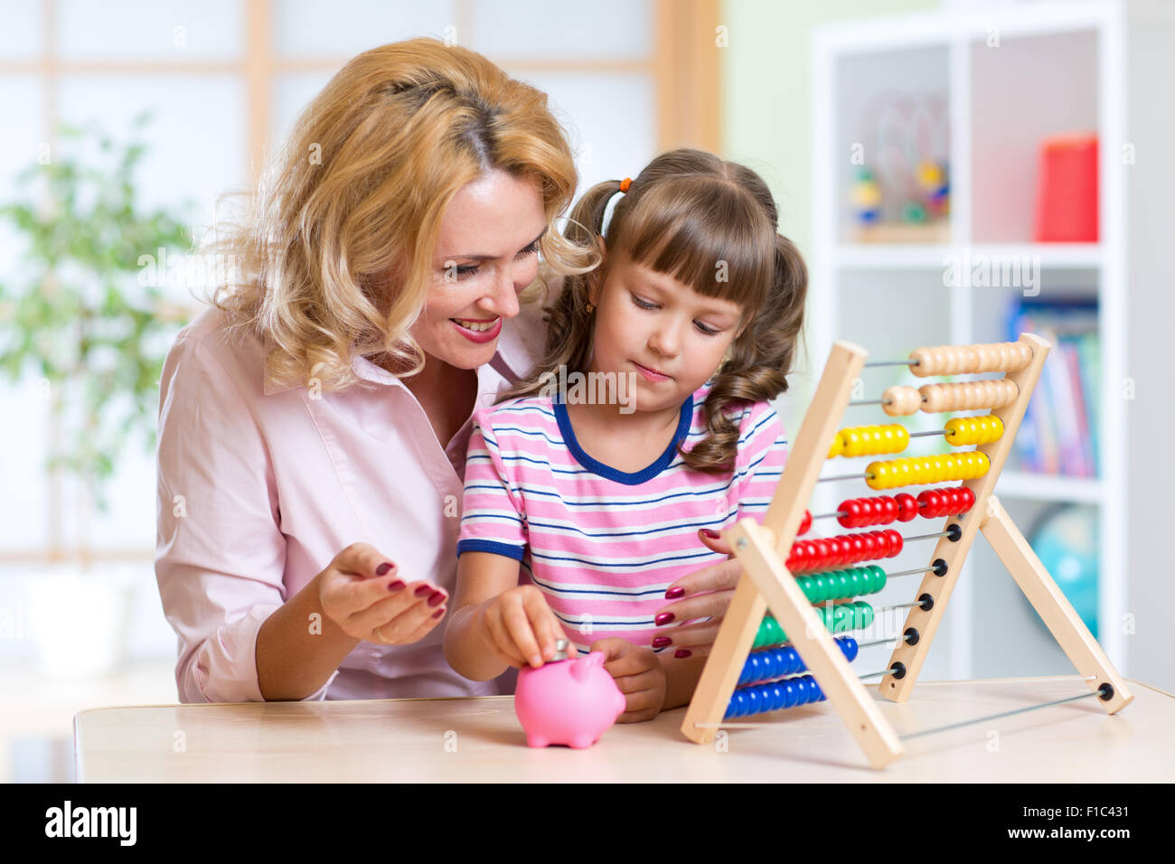 Mother and daughter putting coins into piggy bank Stock Photo - Alamy