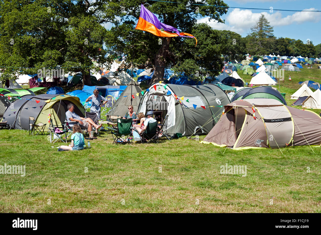 People sitting in camping chairs outside their tents at the campsite at the Port Eliot festival Cornwall UK Stock Photo