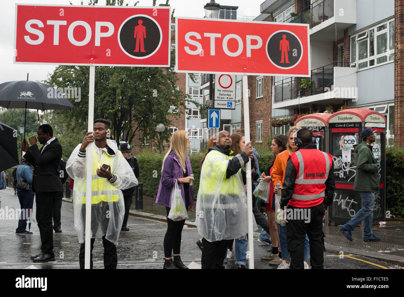 Notting Hill Carnival 2015. Security guards holding stop signs to enable carnival procession to pass Stock Photo