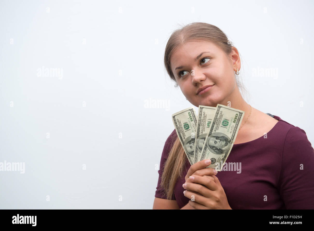 Young  woman holding cash dollars in hand and thinking about money on the white background Stock Photo