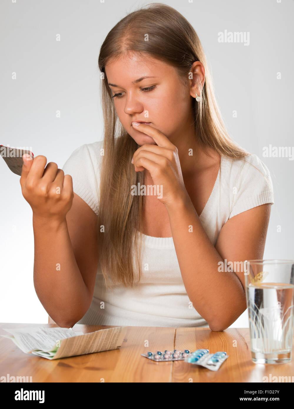 Young woman on the white background, holding in hands medication and