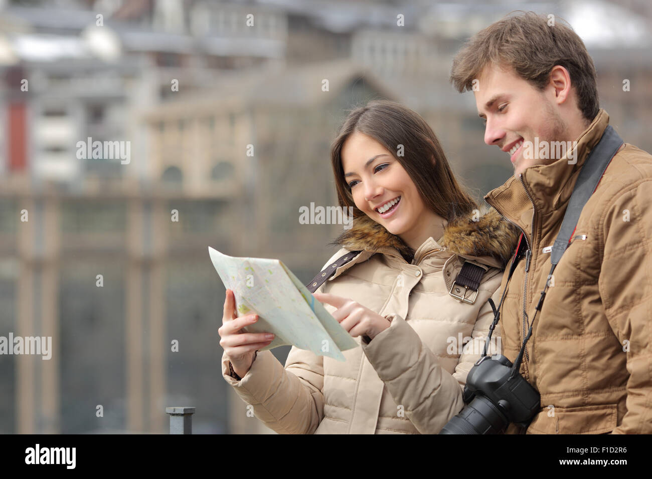 Couple of tourists consulting a guide in winter with an urban background Stock Photo