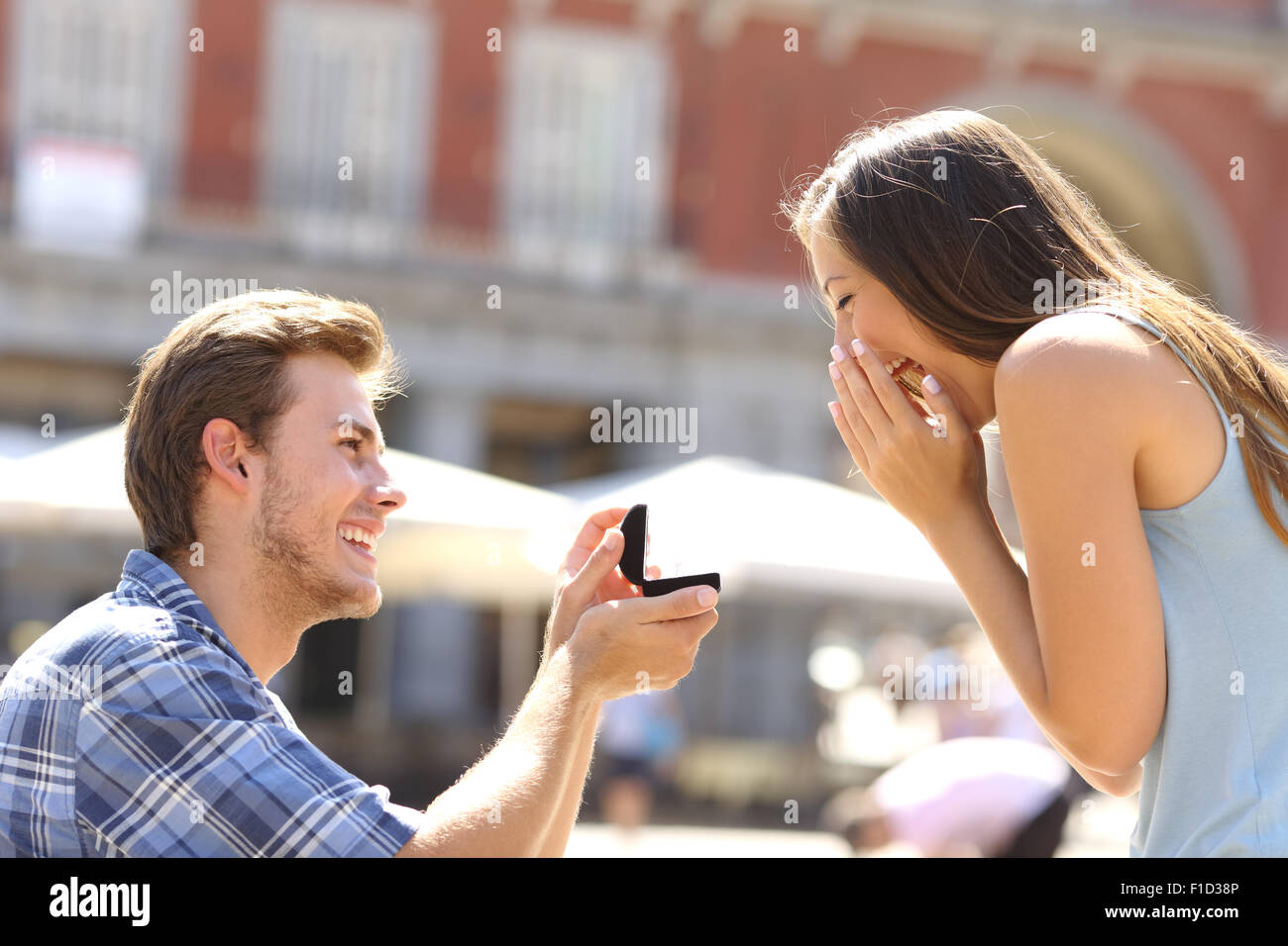 Proposal in the street with a man asking marry to his happy girlfriend Stock Photo