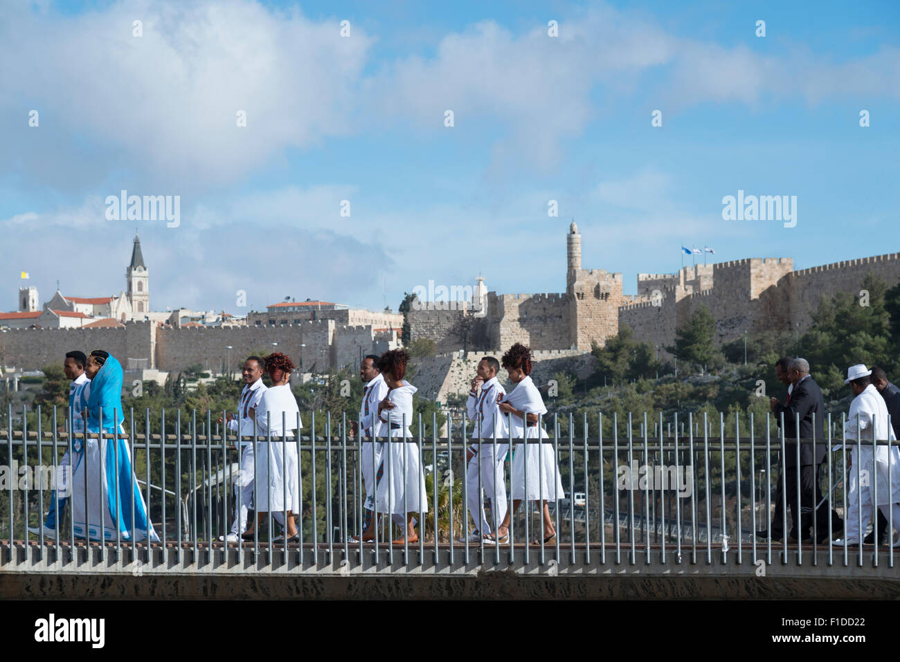 Ethiopian migrants party crossing a pedestrian bridge with Jerusalem Old City in background. Jerusalem. Israel. Stock Photo