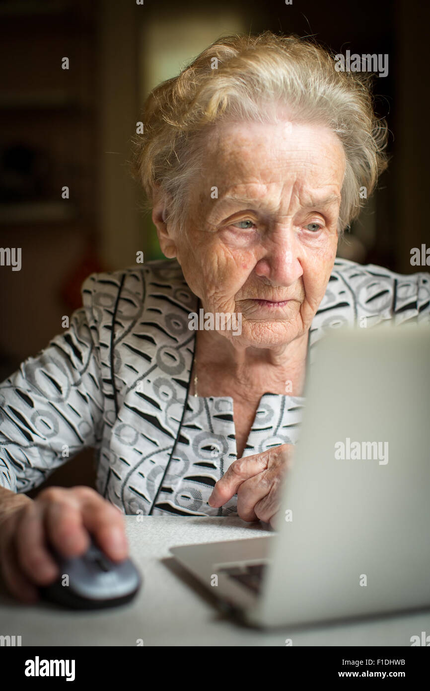 An elderly woman working on a laptop. Senior woman with computer. Stock Photo