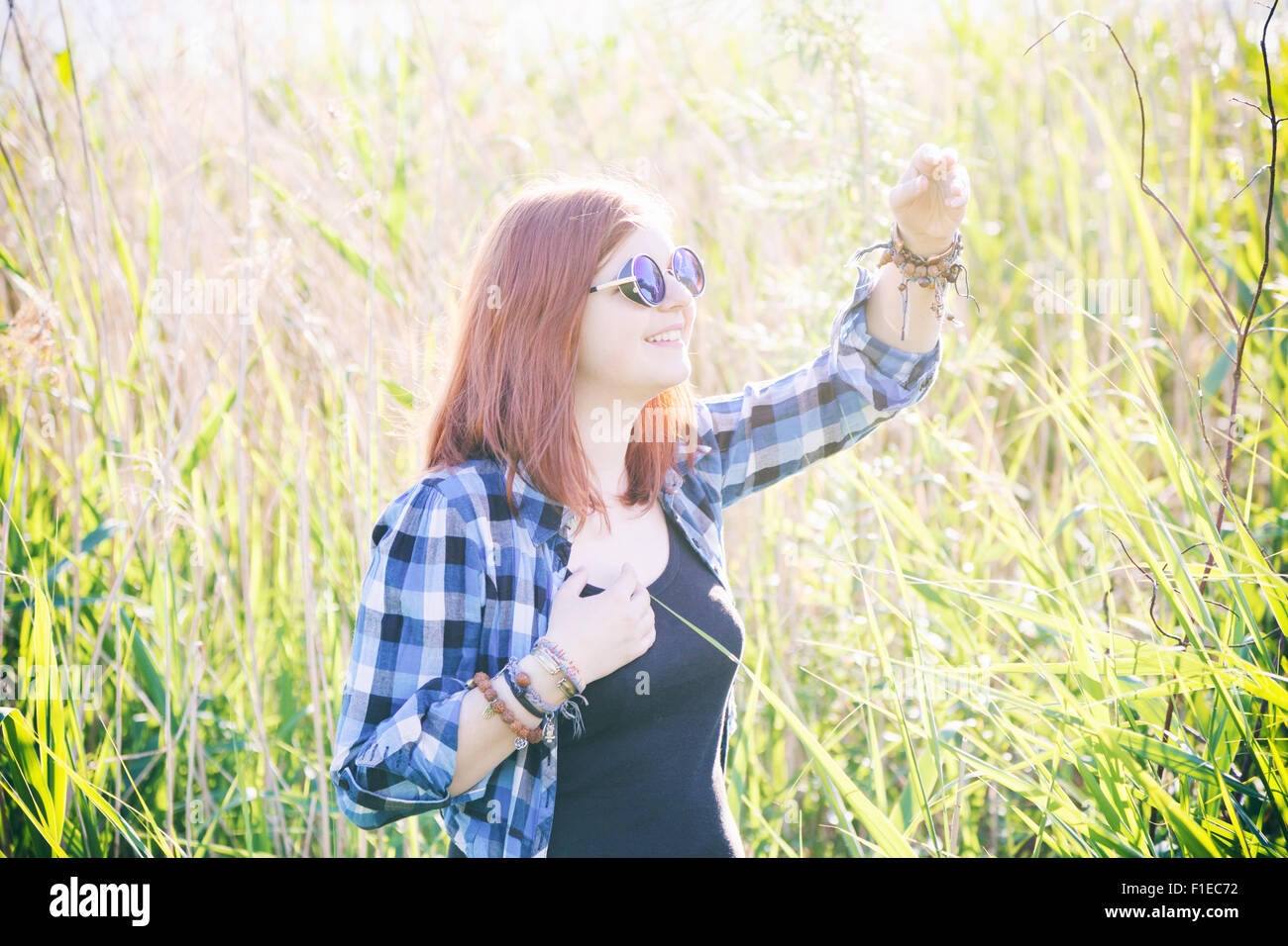 Vintage stylized photo of happy beautiful young woman on summer meadow in tall grass. Stock Photo