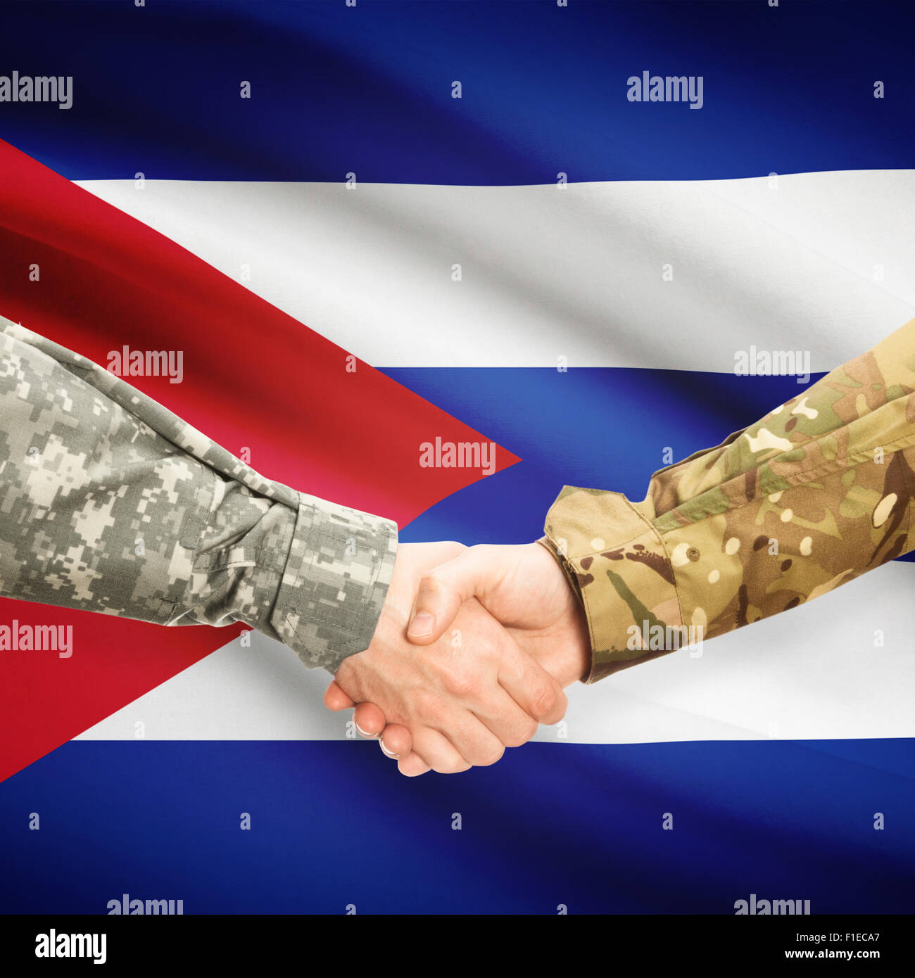 Soldiers shaking hands with flag on background - Cuba Stock Photo