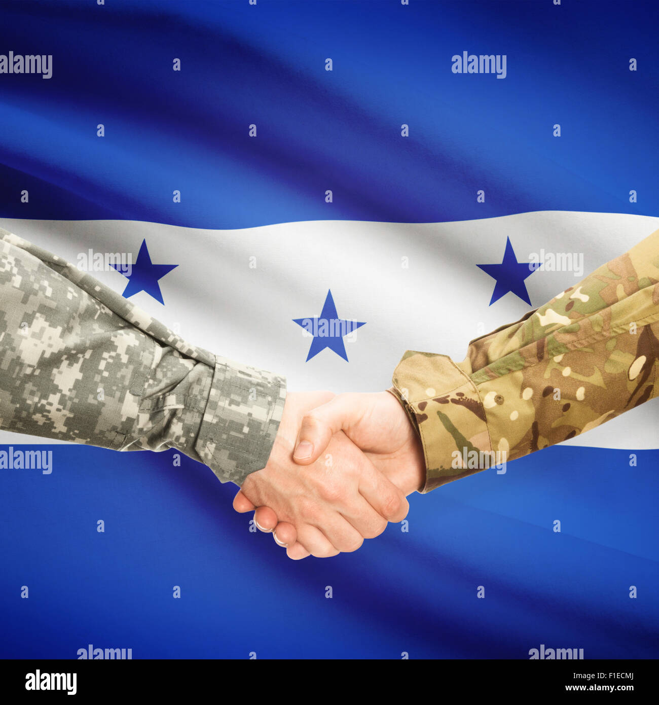 Soldiers shaking hands with flag on background - Honduras Stock Photo