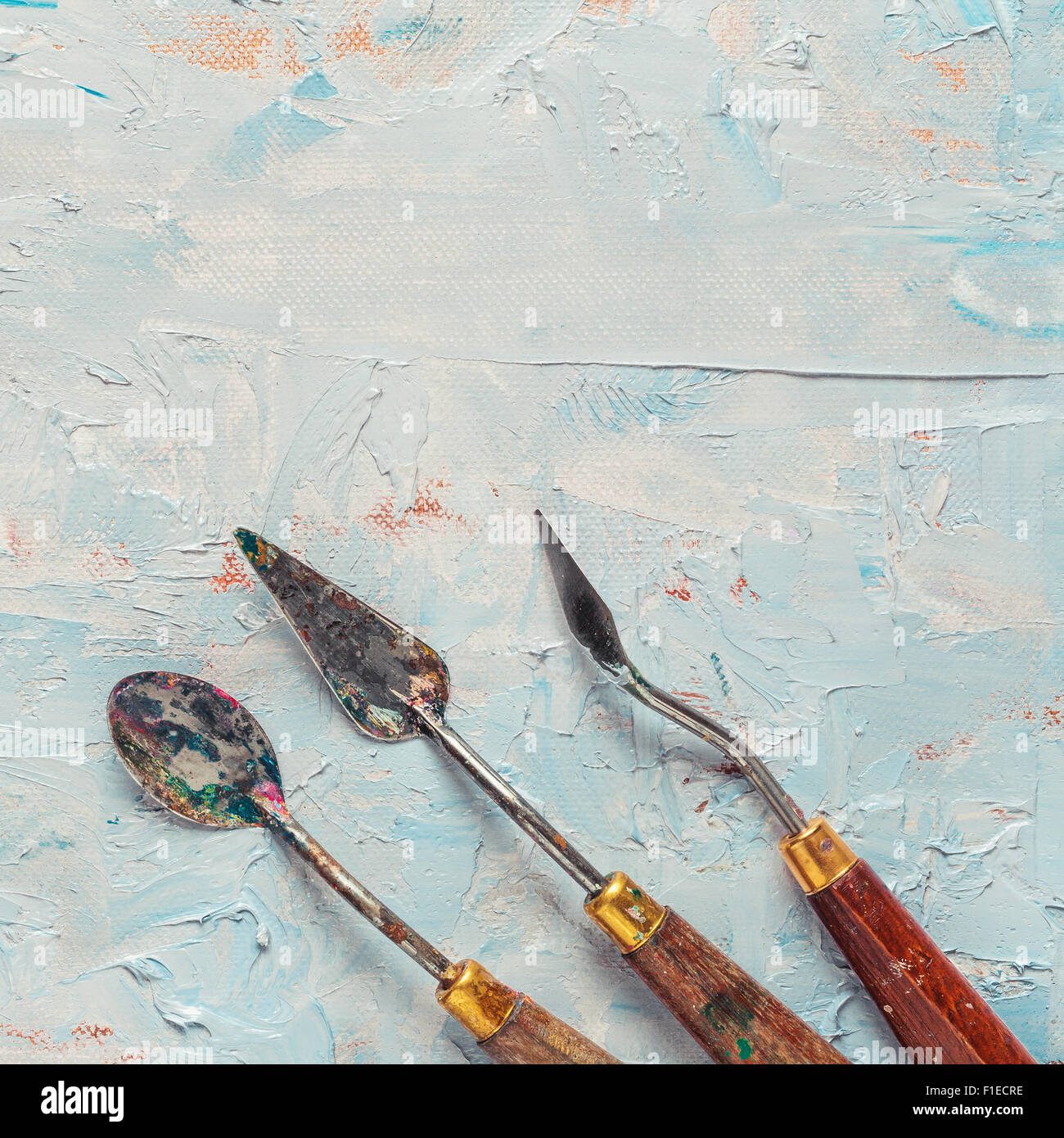 Old palette knifes on artist canvas with oil paint Stock Photo