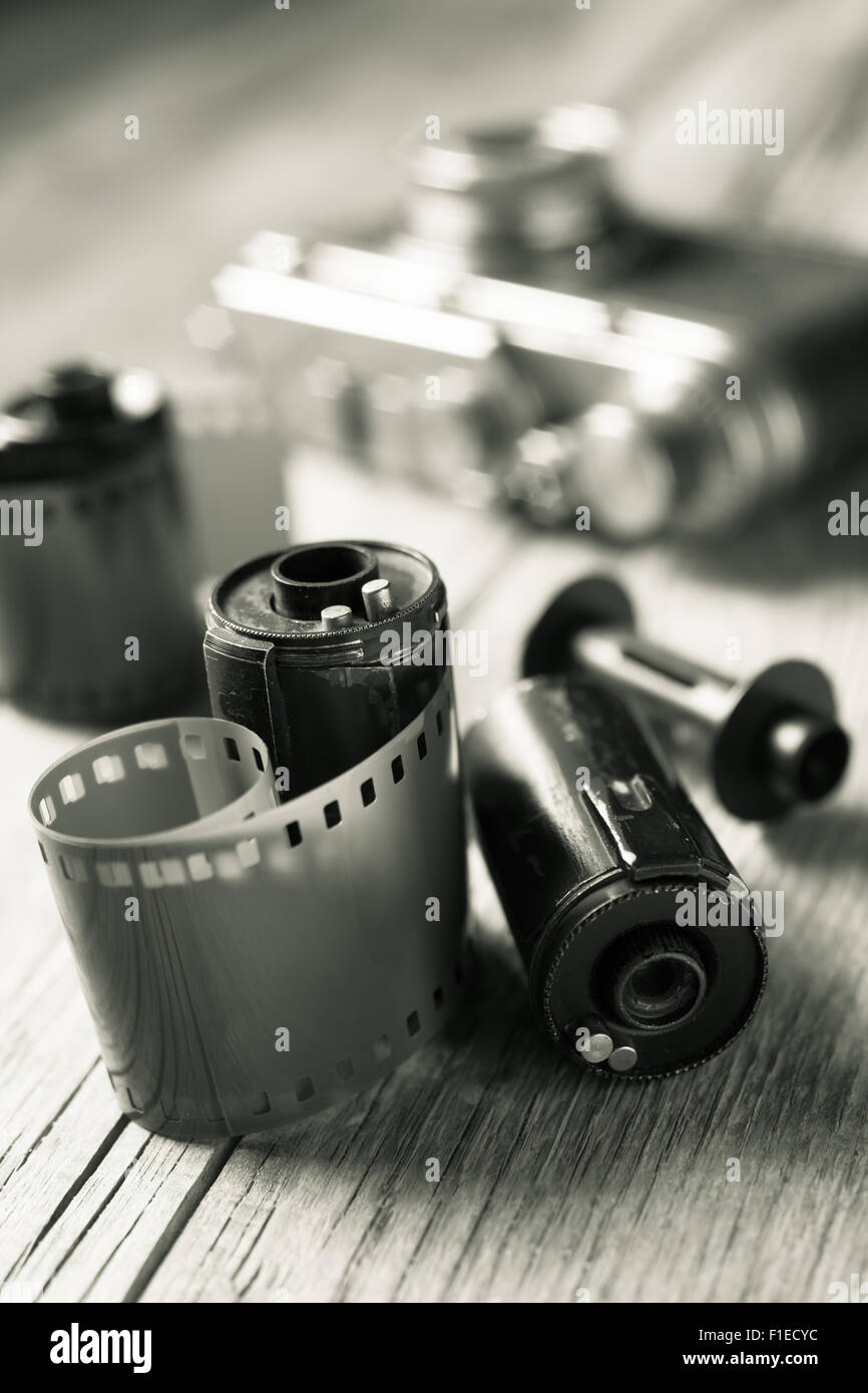 Old photo film rolls, cassette and retro camera on background. Black and white stylized. Stock Photo
