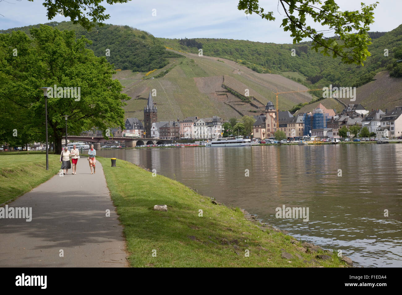 People walking along riverside path Urzig alongside Mosel River Germany Stock Photo