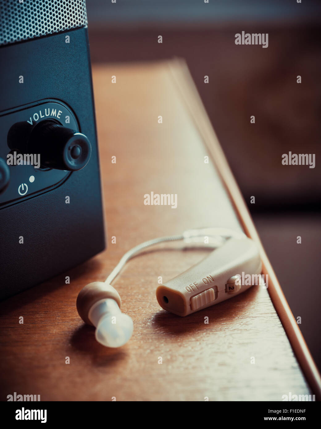 Hearing aid and music speaker on desk. Vintage stlylized photo. Stock Photo