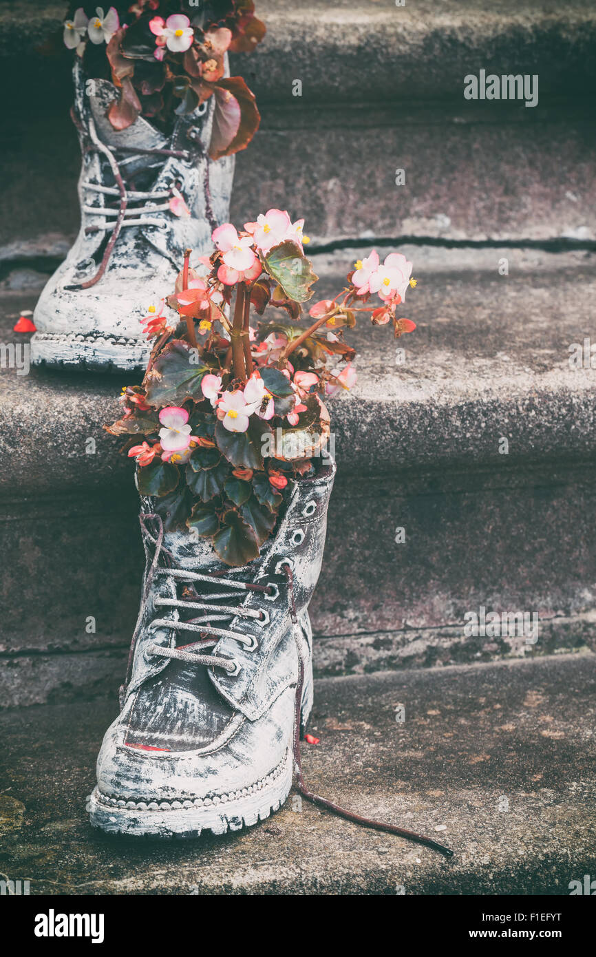 Old boots with flowers as element of garden design. Selective focus. Stock Photo
