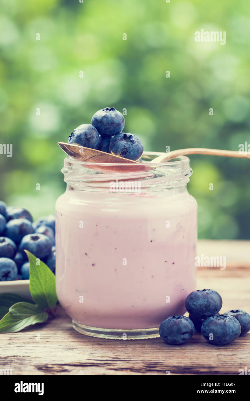 Fresh blueberries yogurt in glass jar. Retro stylized. Stock Photo
