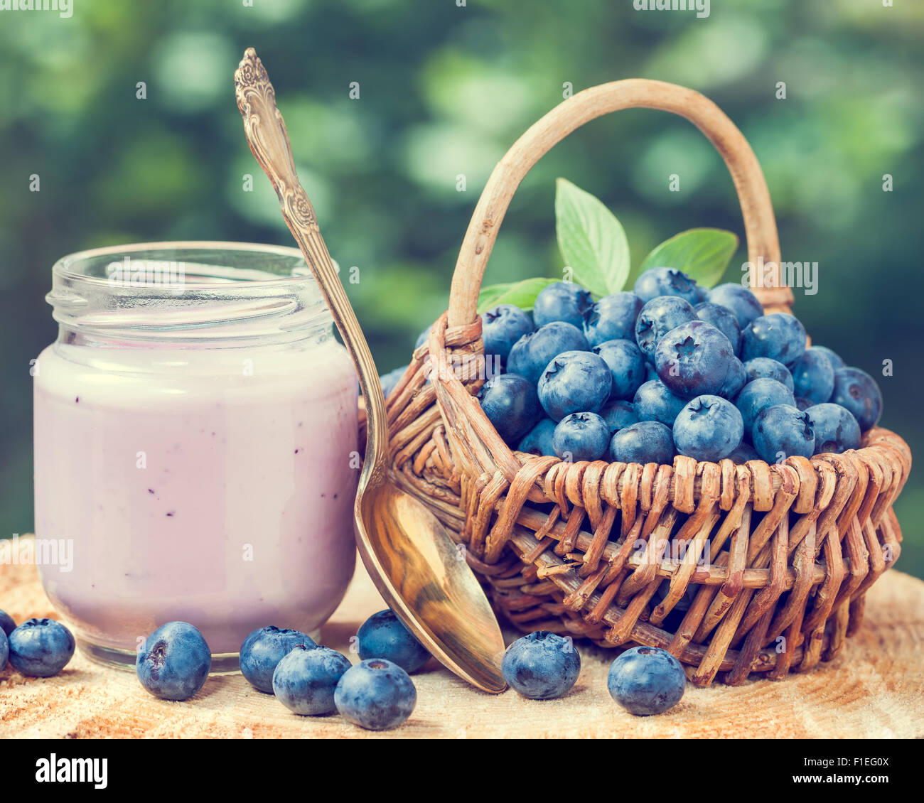 Fresh blueberries yogurt in glass jar and wicker basket with bilberries. Stock Photo