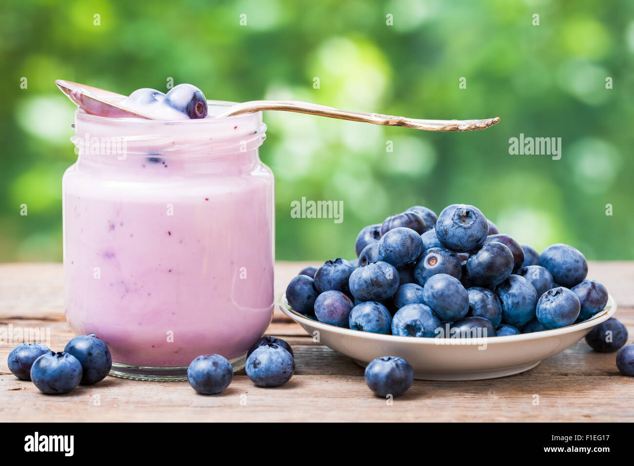 Fresh blueberries yogurt in glass jar and saucer with bilberries. Stock Photo
