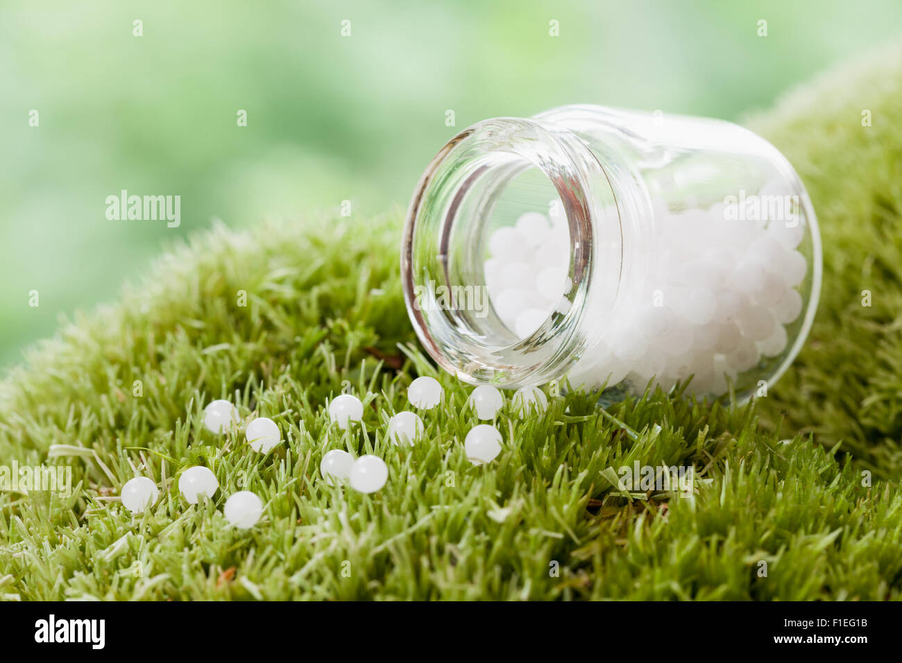 Bottle of homeopathy globules on green moss. Selective focus. Stock Photo