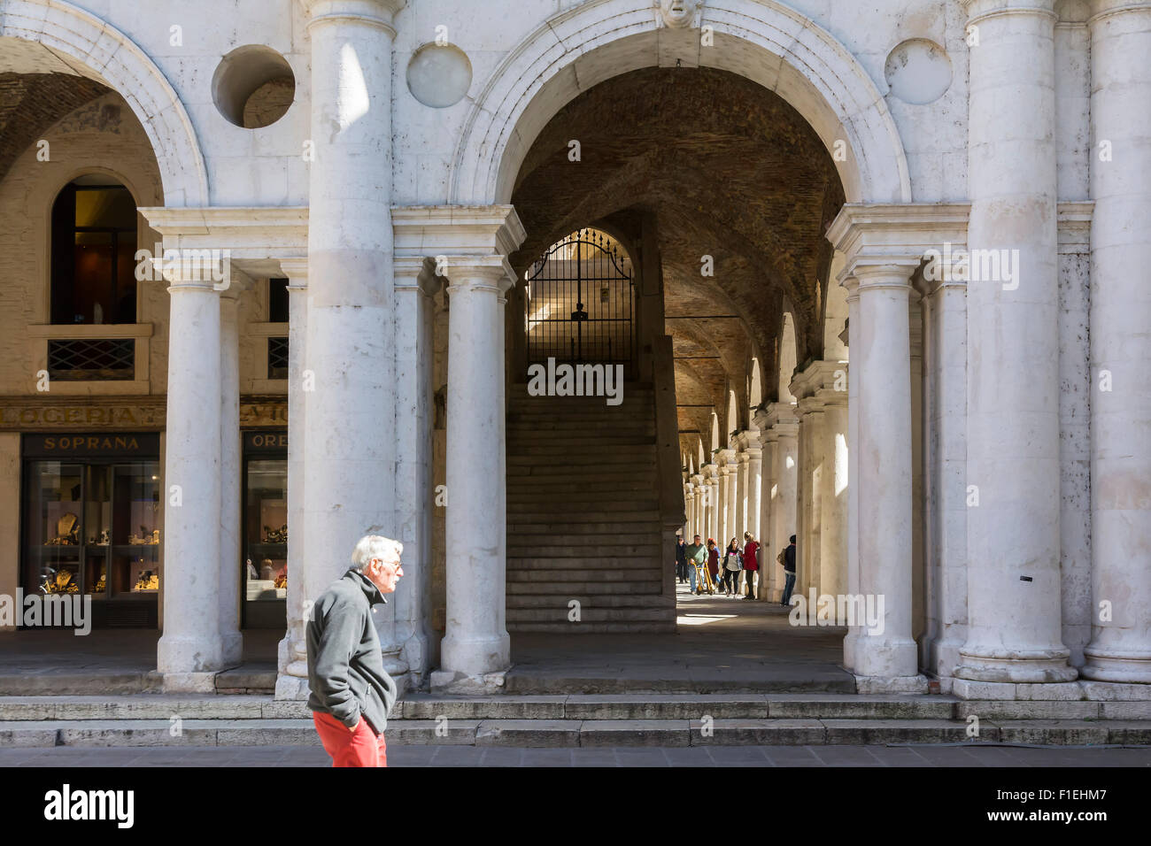 Vicenza,Italy-April 3,2015:old man stroll near of the colonnade of the Palladian basilica in the center of Vicenza during a sunn Stock Photo