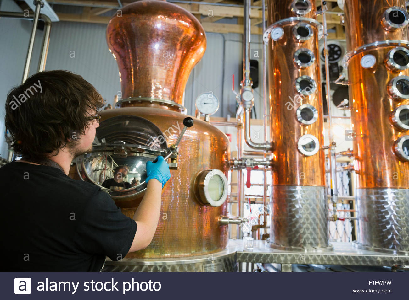 Worker checking copper distillery vats Stock Photo