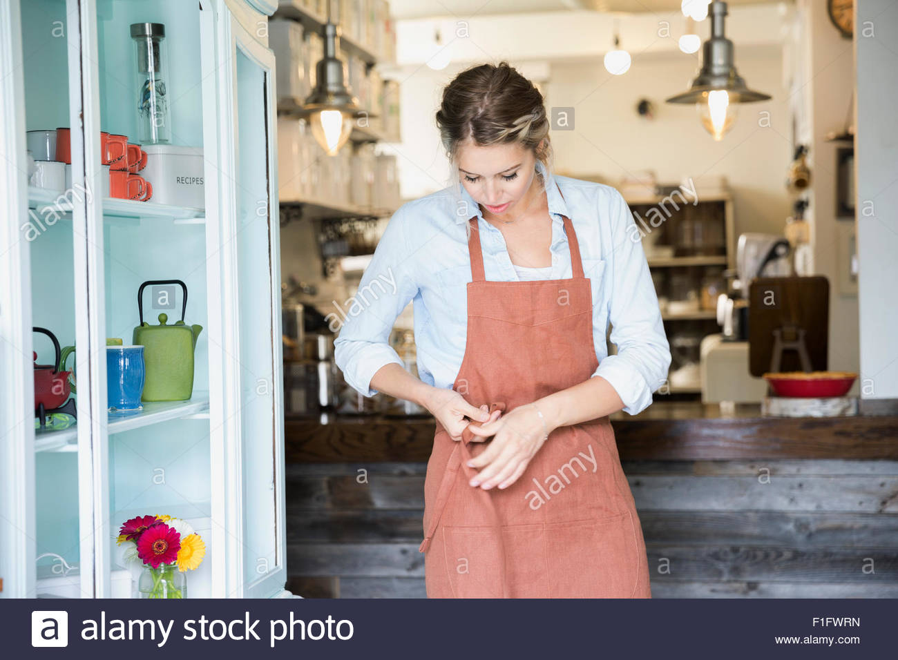 Tea shop owner tying apron Stock Photo - Alamy