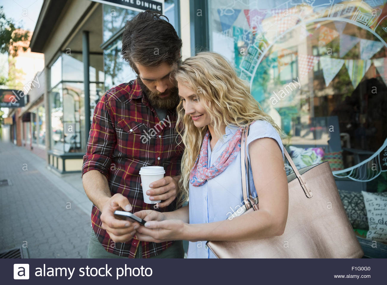 Couple texting with cell phone outside storefront Stock Photo