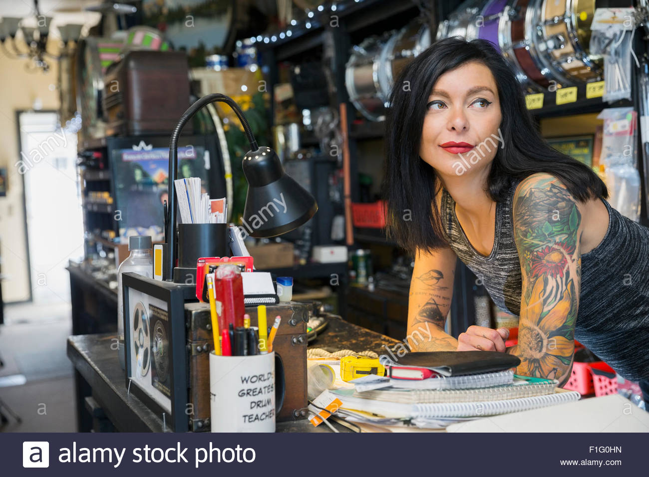 Music shop owner with tattoos leaning on counter Stock Photo