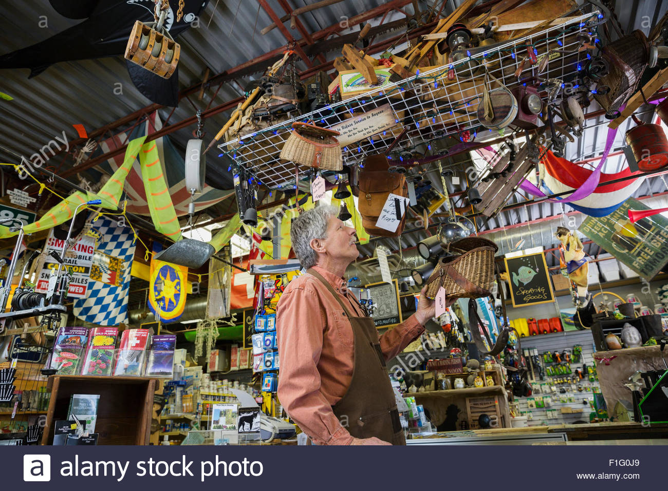 Hardware store owner checking hanging display of fishing baskets Stock