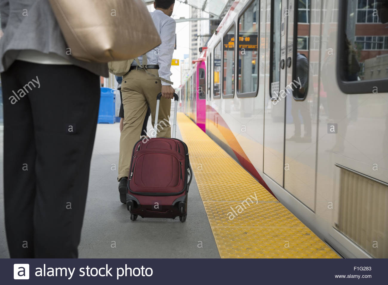 Businessman pulling suitcase along train on platform Stock Photo