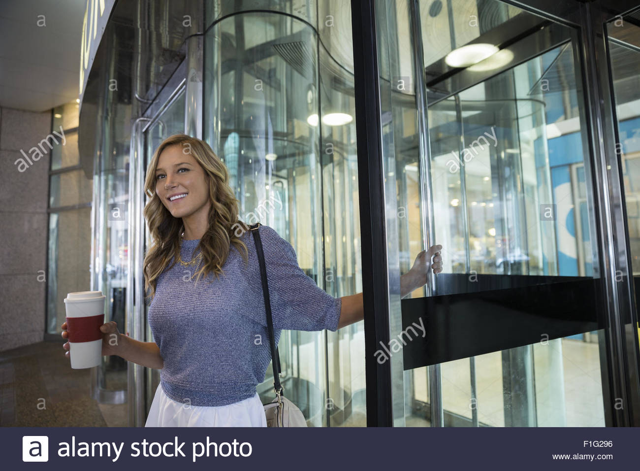 Businessman with coffee cup at revolving door Stock Photo