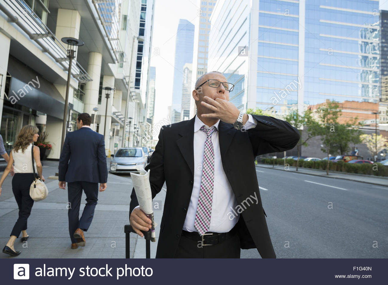 Businessman whistling hailing taxi on city street Stock Photo