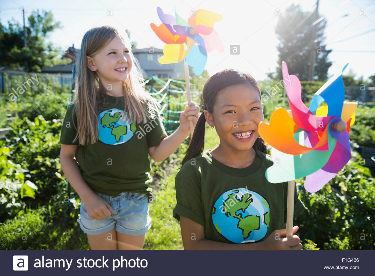 Portrait smiling girls with pinwheels in sunny garden Stock Photo