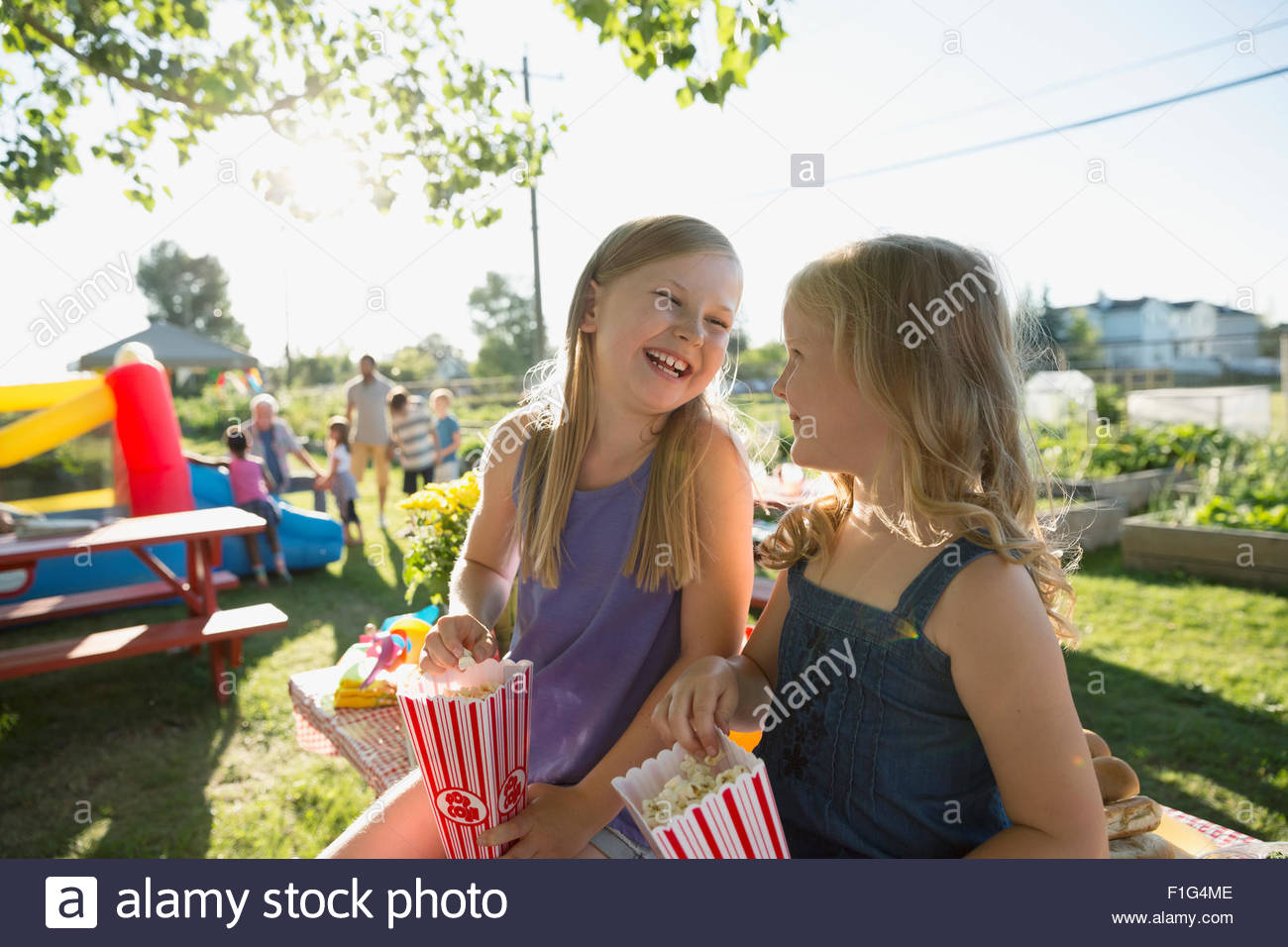 Laughing sisters eating popcorn in park Stock Photo Alamy