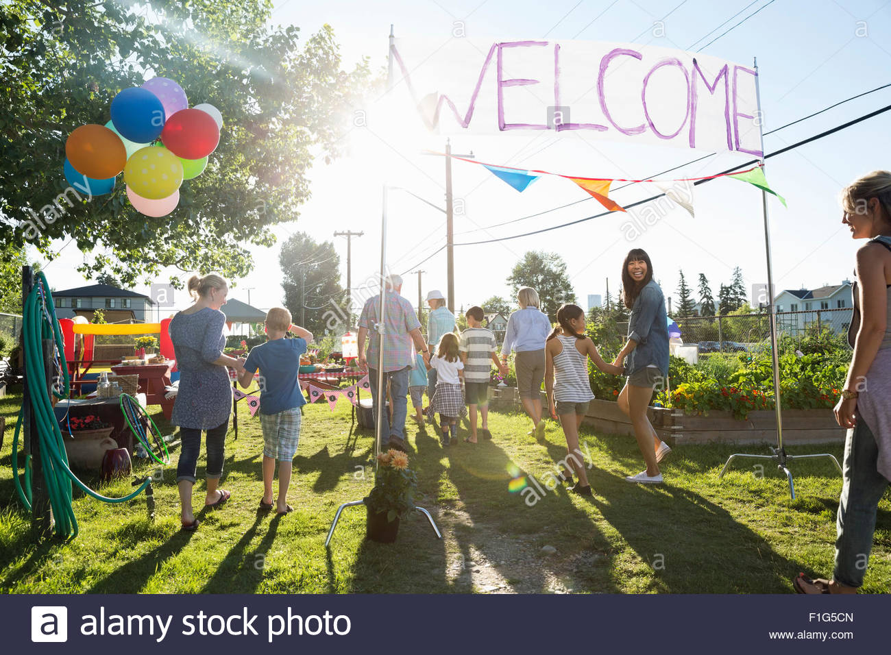 Neighbors entering under Welcome sign party in park Stock Photo