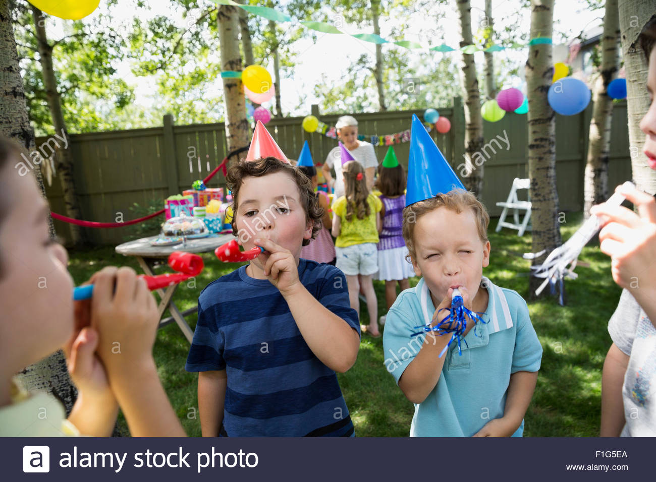 Kids in birthday party hats blowing party favors Stock Photo