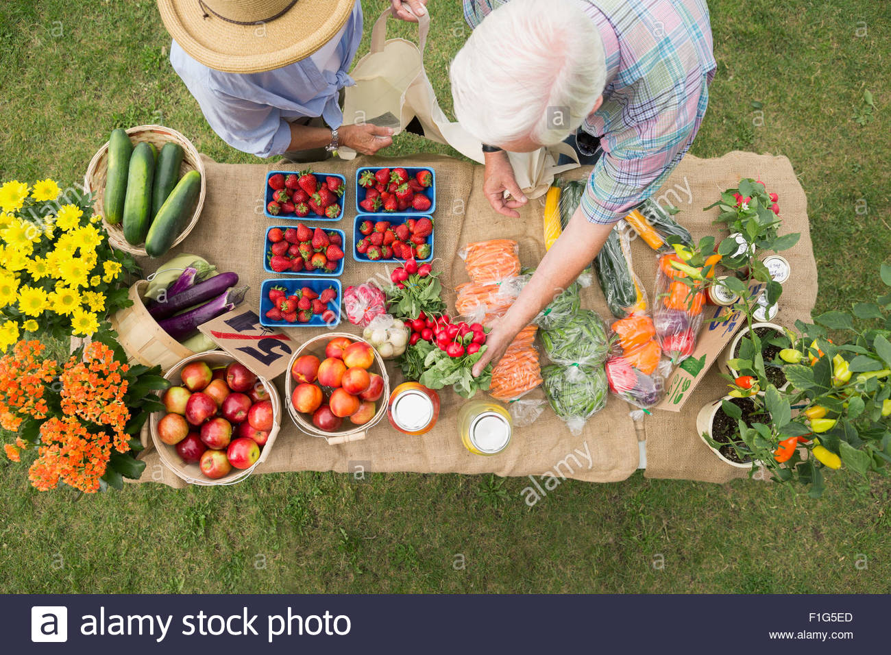 Shoppers reaching produce on farmers market display table Stock Photo