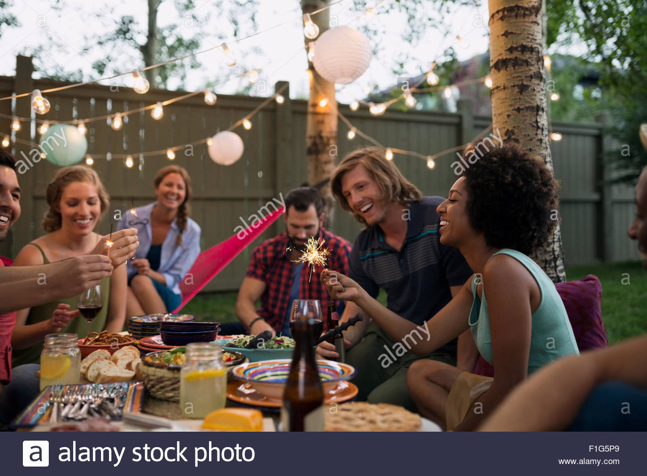 Friends with sparklers at backyard dinner party Stock Photo