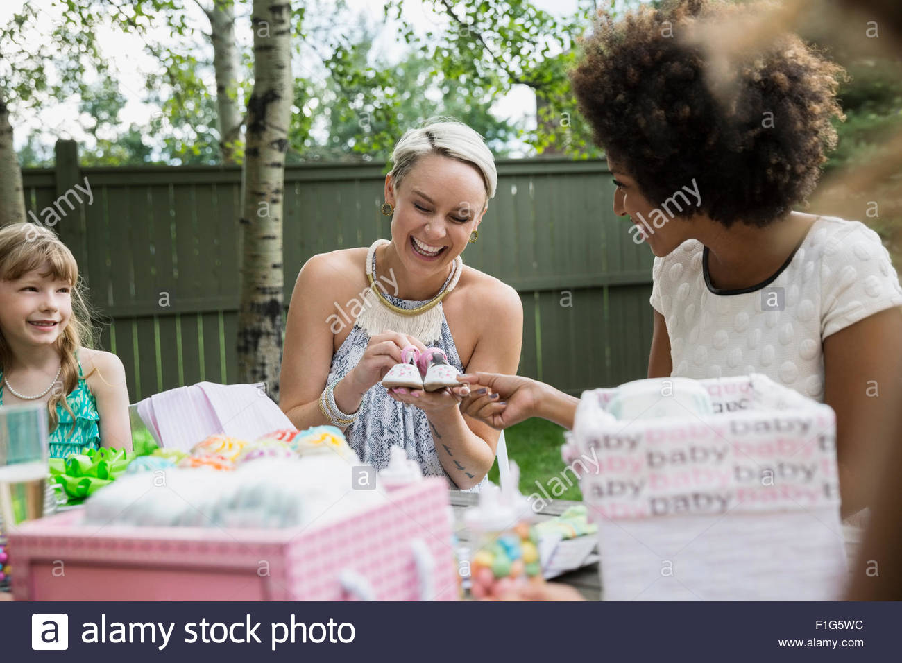 Women admiring tiny baby shoes at baby shower Stock Photo