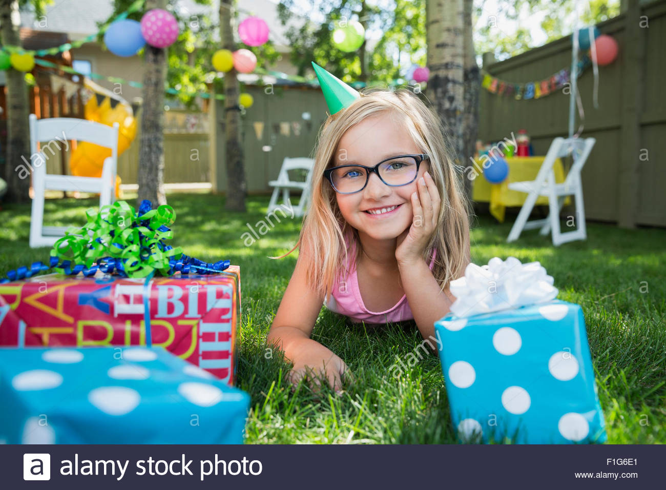 Portrait smiling girl birthday party hat gifts grass Stock Photo