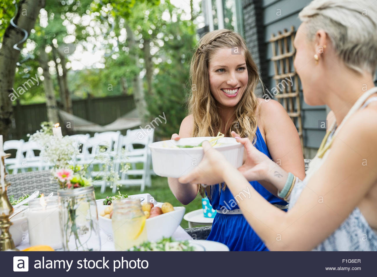 Smiling women passing food at garden party lunch Stock Photo