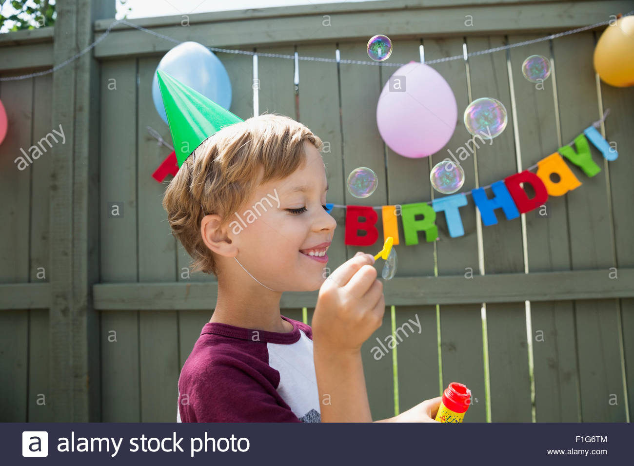 Boy wearing birthday party hat blowing bubbles Stock Photo Alamy