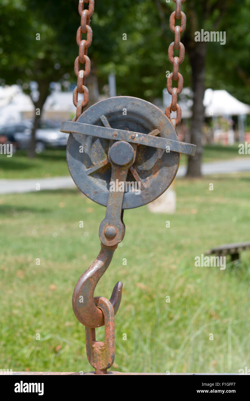 Rusty hook with gear, pulleys and chain on crane for lifting heavy