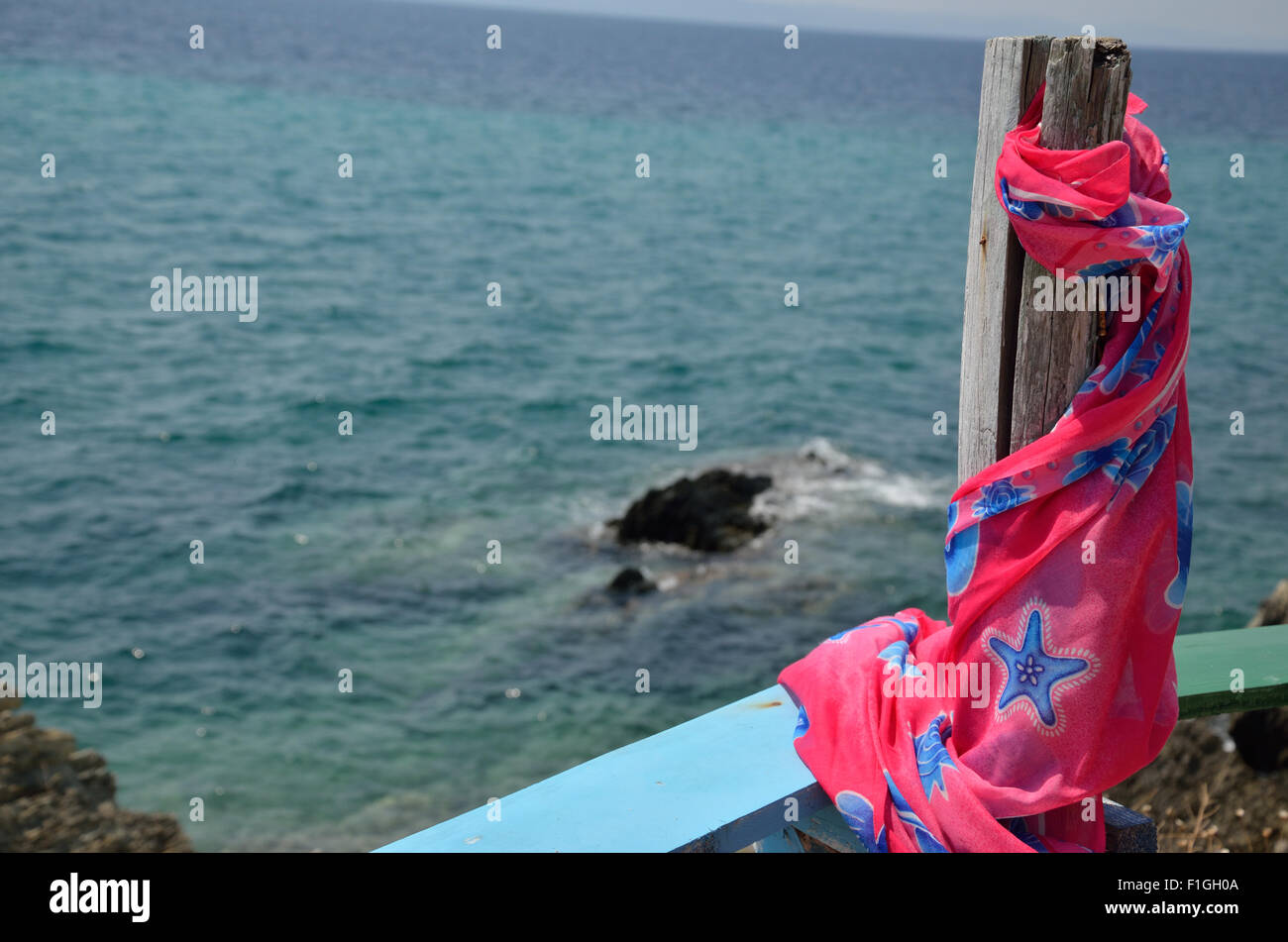 Pink and blue summer pareo scarf on wooden column over sea Stock Photo