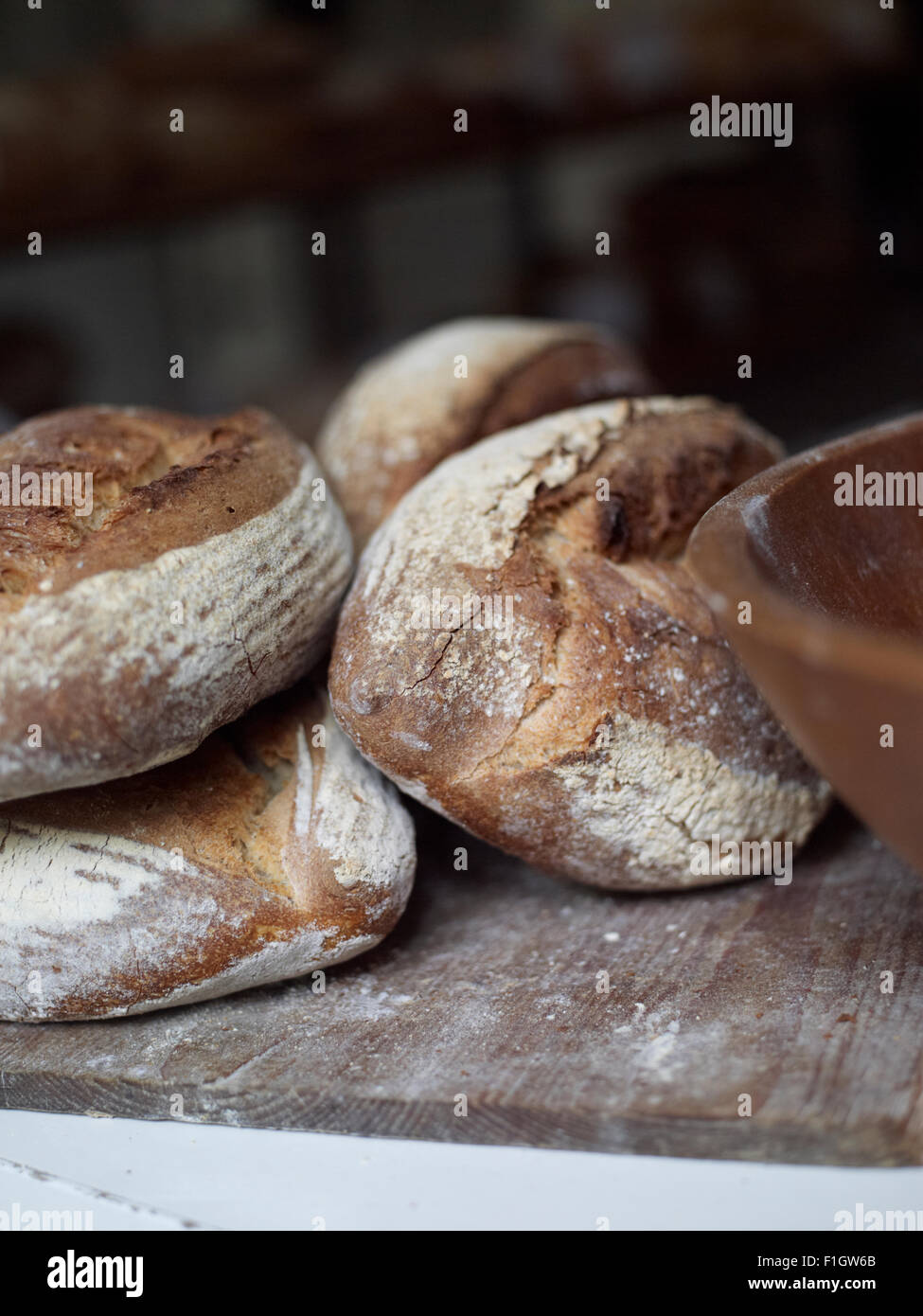 Handmade, traditional loaves of bread, with a bowl, displayed on a chopping board. Stock Photo