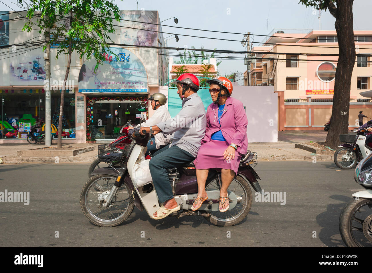 Senior people motorbike, an elderly couple speed through rush-hour traffic on a motorcycle in Tran Hung Dao in Ho Chi Minh City, Saigon, Vietnam Stock Photo