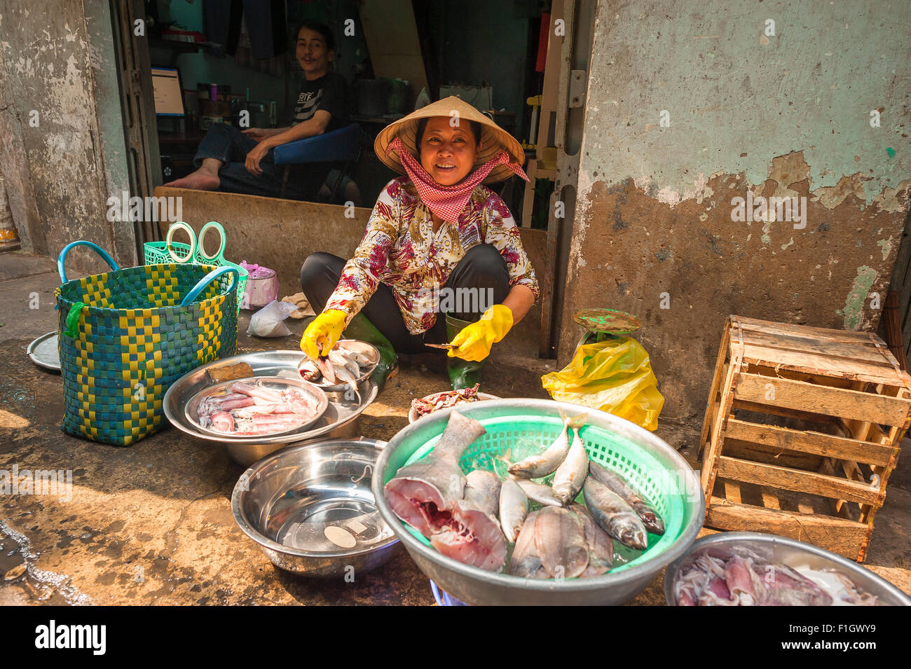 Vietnam woman smiling, in Ho Chi Minh City a Vietnamese woman smiles as she sets out her fish stall on a sidewalk near the Binh Tay market. Stock Photo
