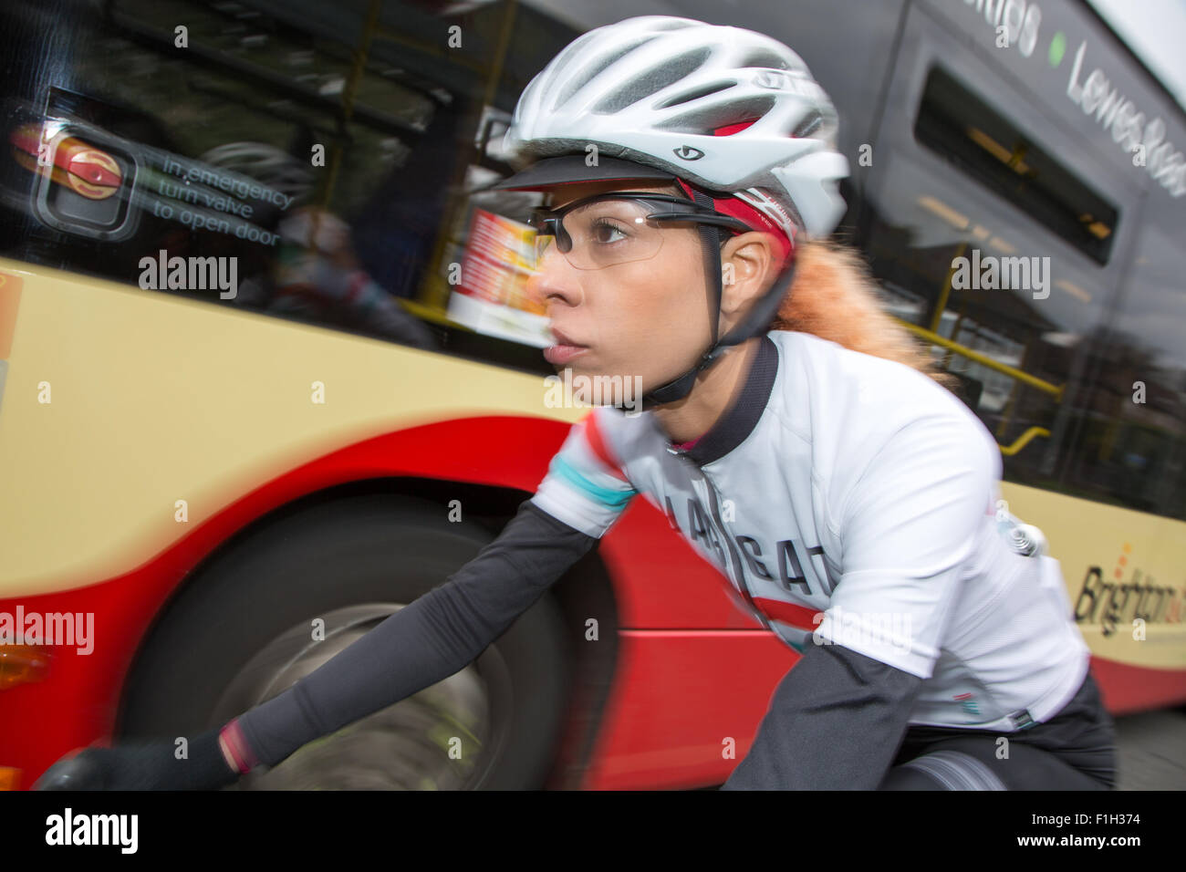 Woman cyclist riding next to a bus in Brighton Stock Photo - Alamy