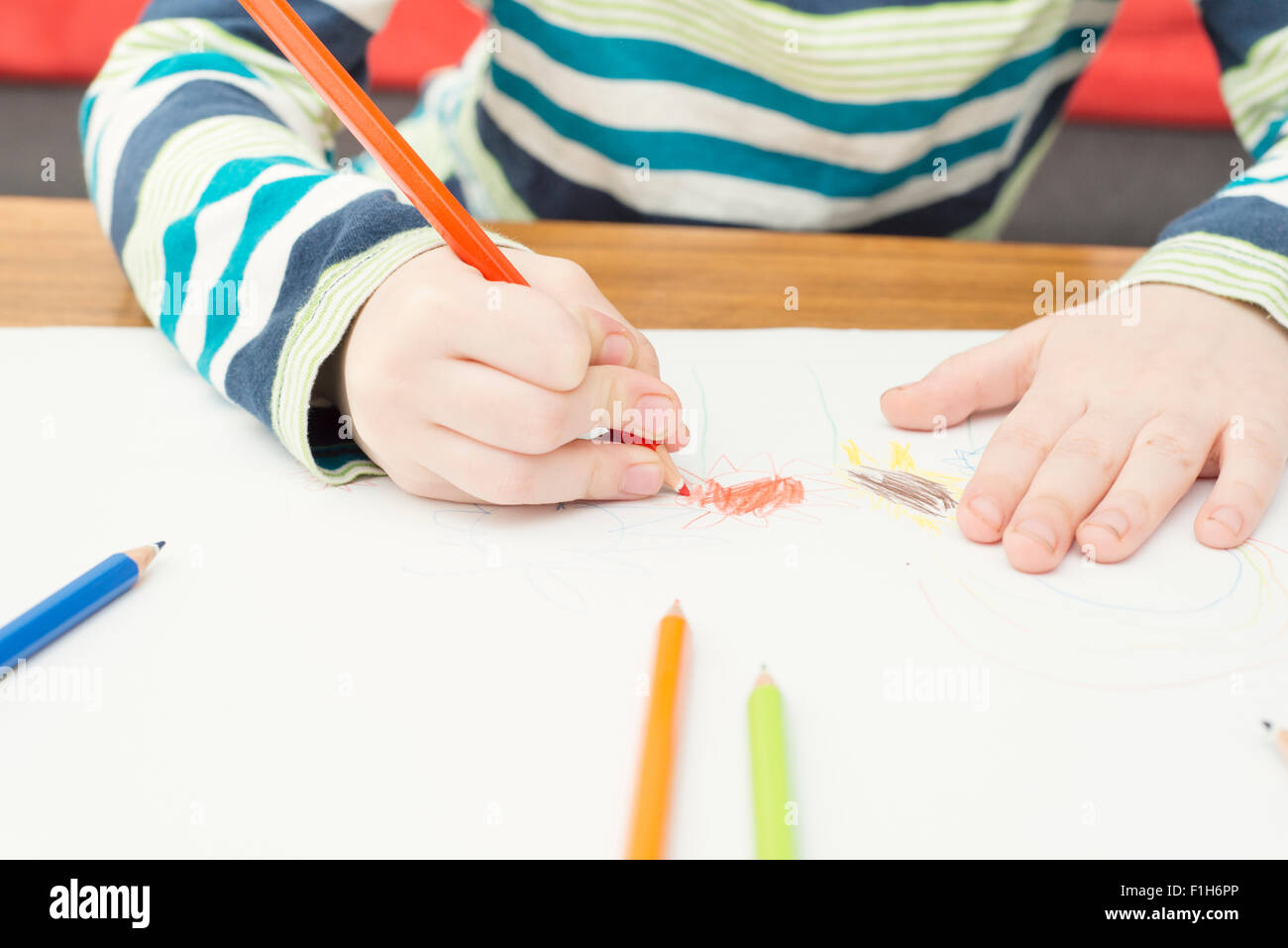 Little girl drawing with colored pencils on white paper. Conceptual image of creativity, childhood fantasy and imagination. Stock Photo