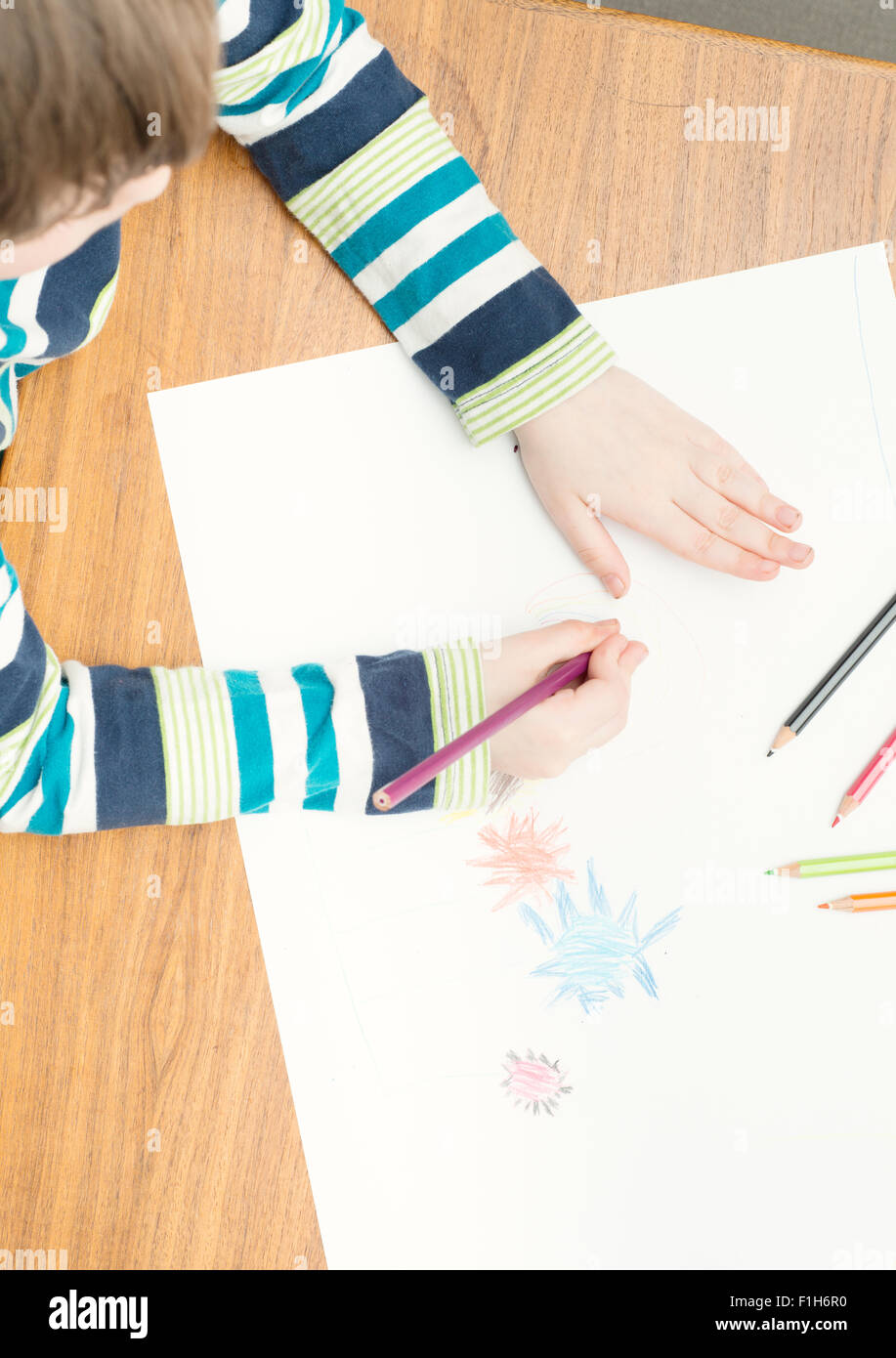 Little girl drawing with colored pencils on white paper. Conceptual image of creativity, childhood fantasy and imagination. Stock Photo